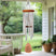 A hanging silver wind chime with an orange top and wooden clapper with wording: Mothers hold their children's hands for a little while but their hearts forever, hanging from the ceiling of a serene outdoor porch.